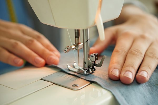 Hands of female tailor using sewing machine at work